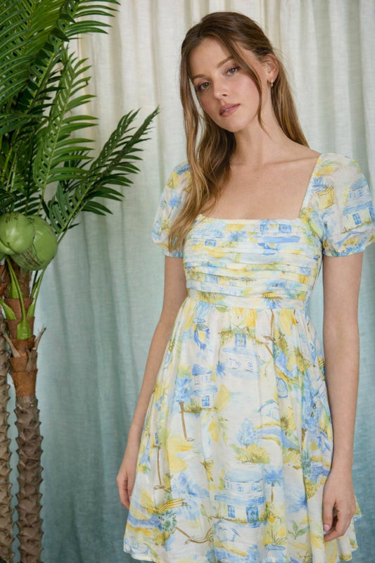 Woman wearing a floral dress standing next to a plant with a light curtain background