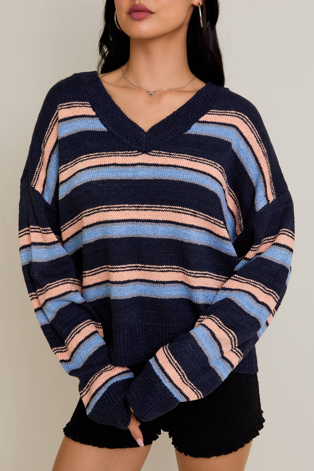 Person wearing a navy, pink, and blue striped sweater against a neutral background